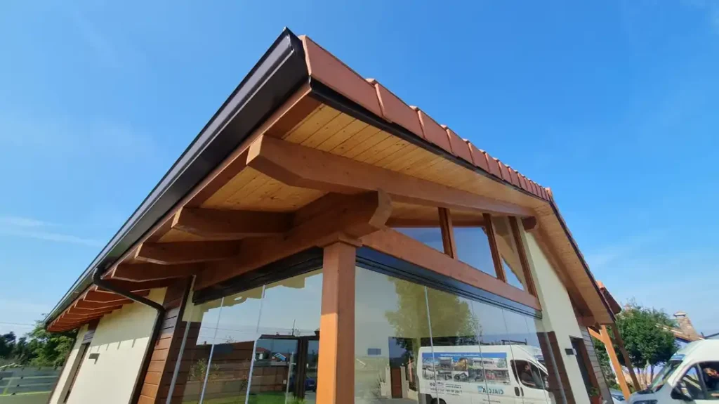 Porche acristalado en Muros de Nalón, Asturias, con mobiliario de exterior en ratán, vistas al jardín y techo de madera. Un espacio luminoso y acogedor ideal para relajarse.