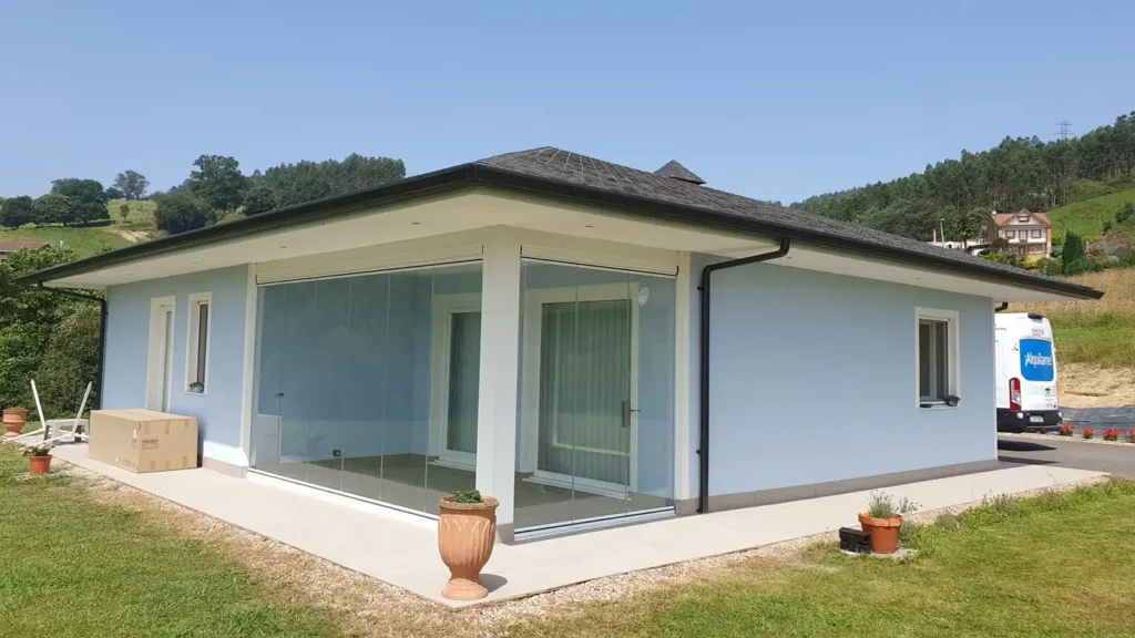 Instalación de cerramiento acristalado sin perfiles en Beranga, Cantabria. Solución Lumon ideal para disfrutar del porche todo el año con ventilación y protección.