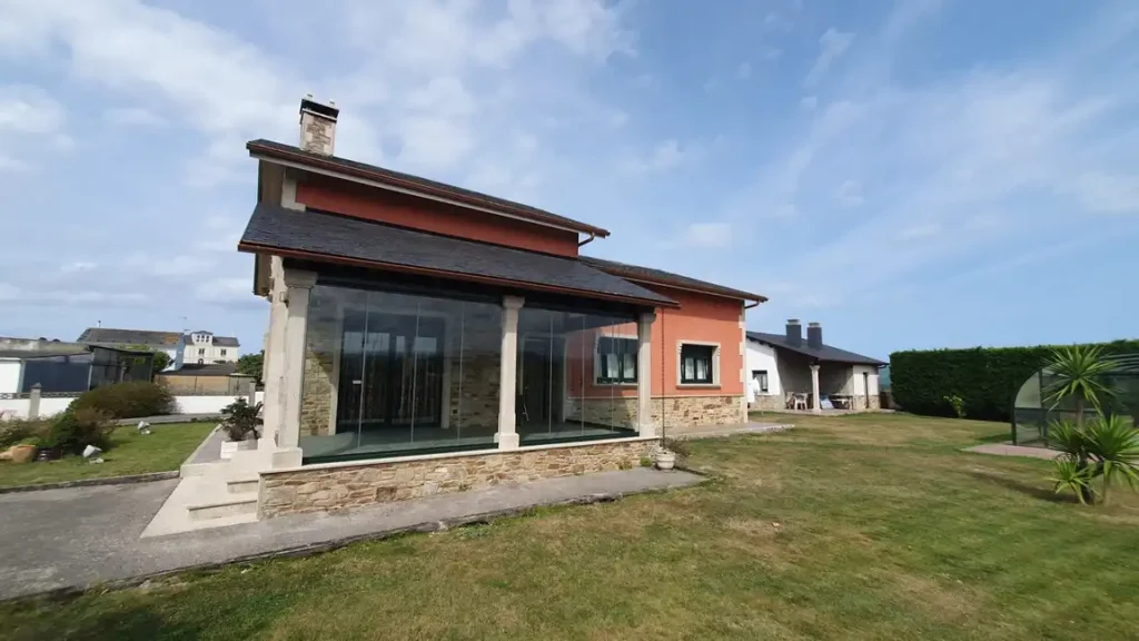 Cerramiento de terraza con cortinas de cristal sin perfiles en vivienda de Asturias.