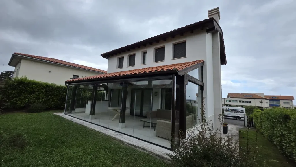 Cerramiento con cortinas de cristal Lumon en porche de madera de un chalet en La Isla, Colunga (Asturias), realizado por Cialca.
